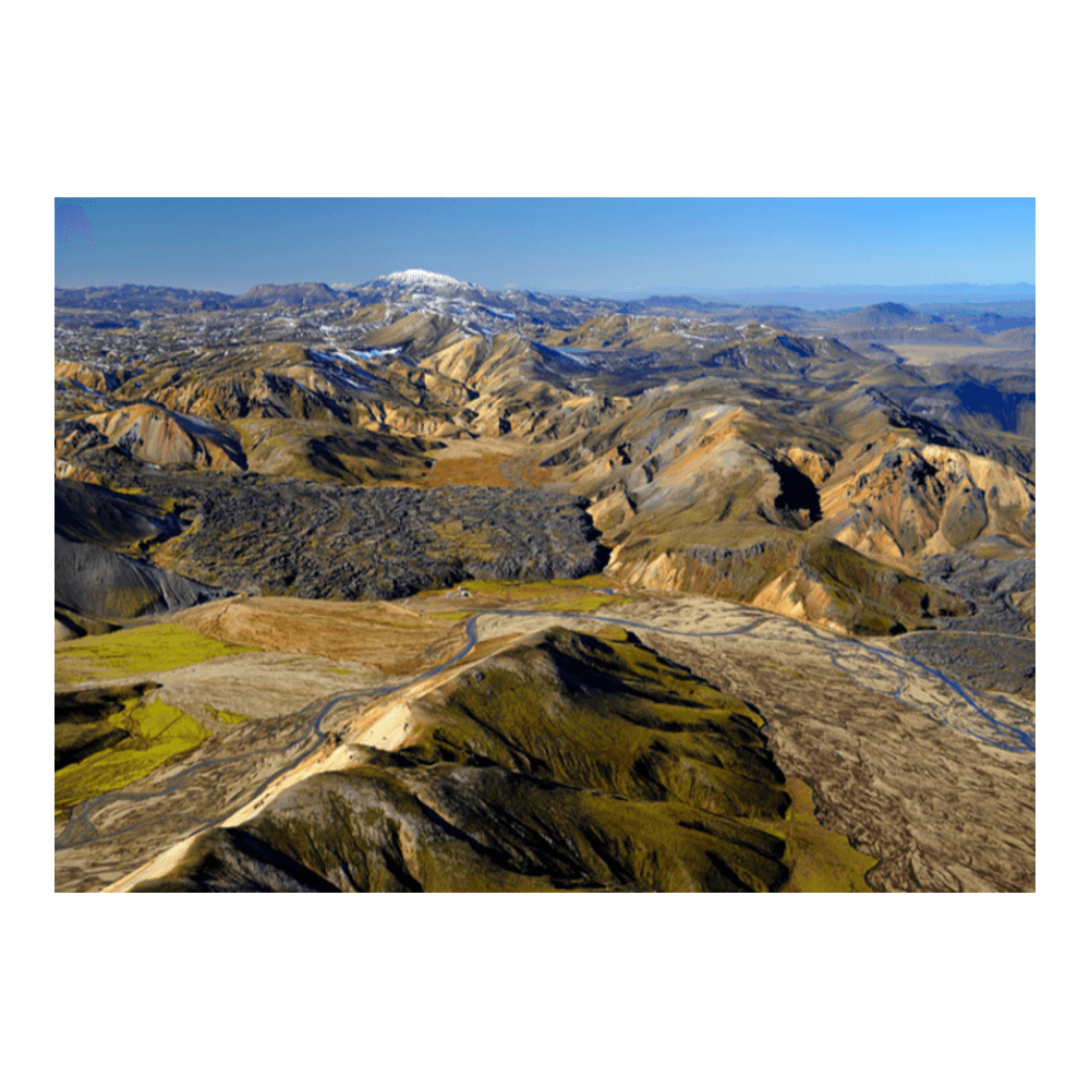 Traditional Icelandic farm — white farmhouse and red barn set against vast volcanic mountains and open sky